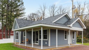 A single-story house with a covered porch, a garage, and a well-maintained lawn. - Cozy 2-bedroom guest house in perfect South Hero with private lake access. (South Hero)