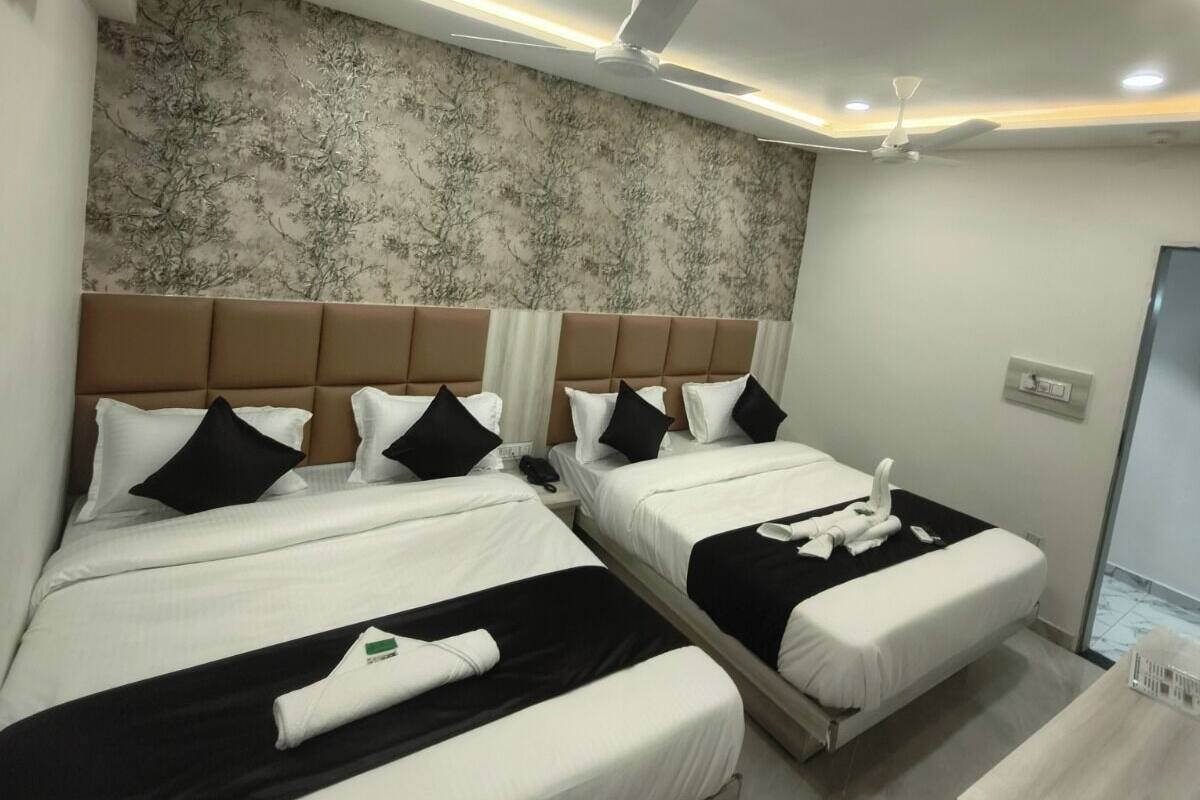 A hotel room with two beds, a marble-patterned wall, ceiling fans, and recessed lighting.