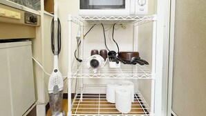 Una cocina con microondas en un estante, un secador de pelo y una tetera.