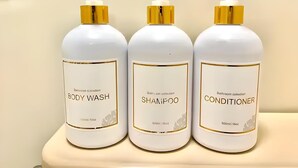 Tres botellas de gel de ducha, champú y acondicionador sobre una estantería.