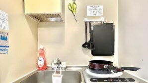 Una cocina con un lavamanos de acero inoxidable, una estufa y diversos utensilios.