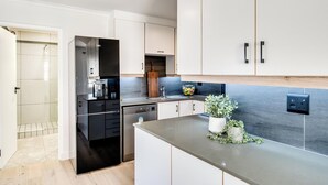 Een moderne keuken met witte kastjes, een grijze aanrechtplaat en een houten snijplank.