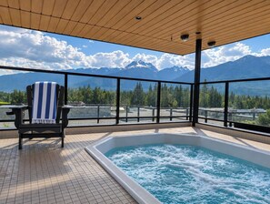 Un jacuzzi con vista a la montaña, una silla con una toalla y techo de madera.