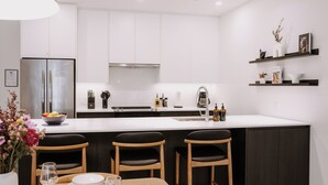 Een moderne keuken met een centraal eiland, witte kasten en een eethoek met houten stoelen.