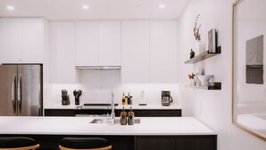 Een moderne keuken met witte kasten, roestvrijstalen apparatuur en een centraal eiland met barstoelen.