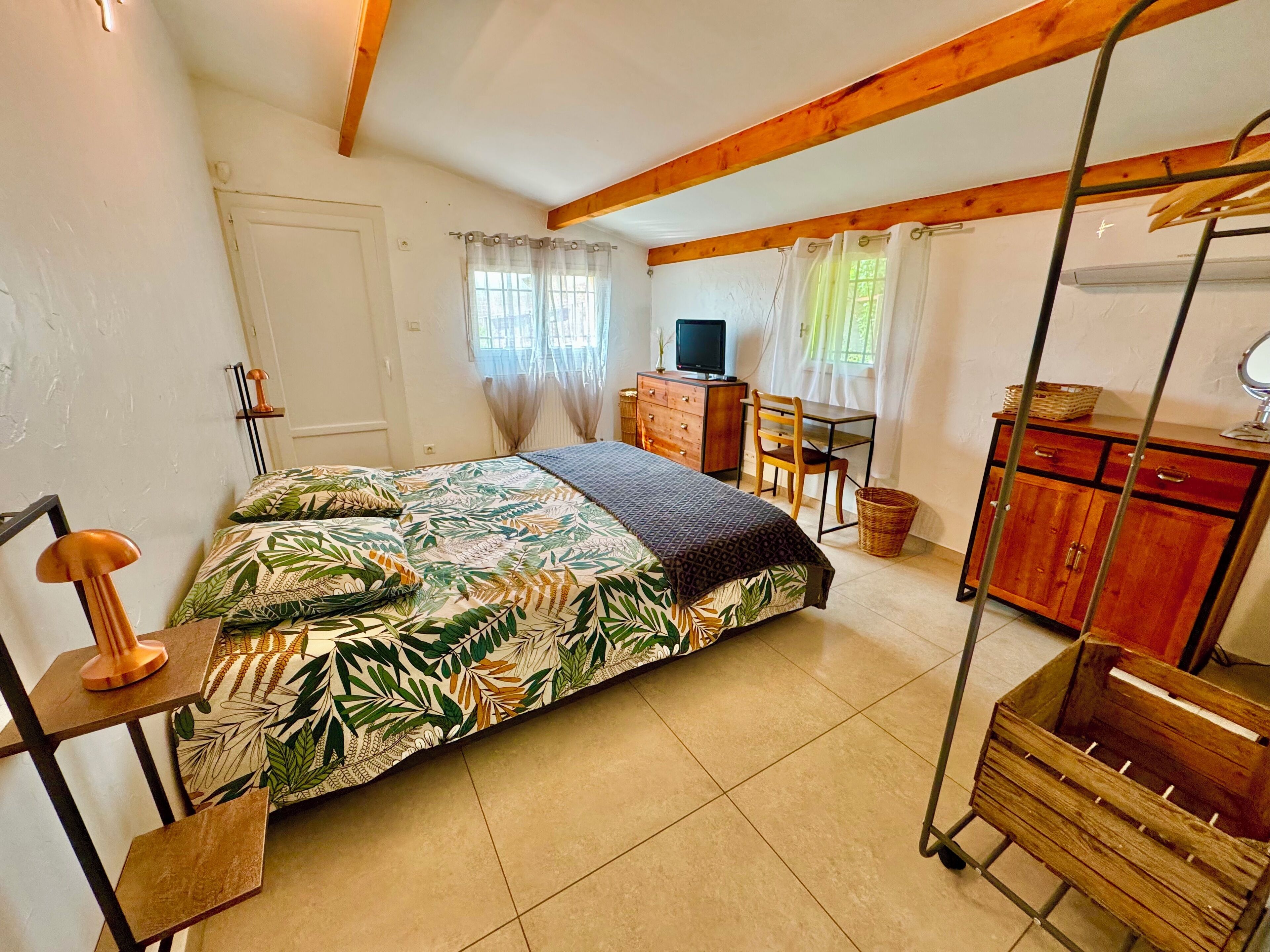A bedroom with a bed, a desk, a chair, a television, and a wardrobe.