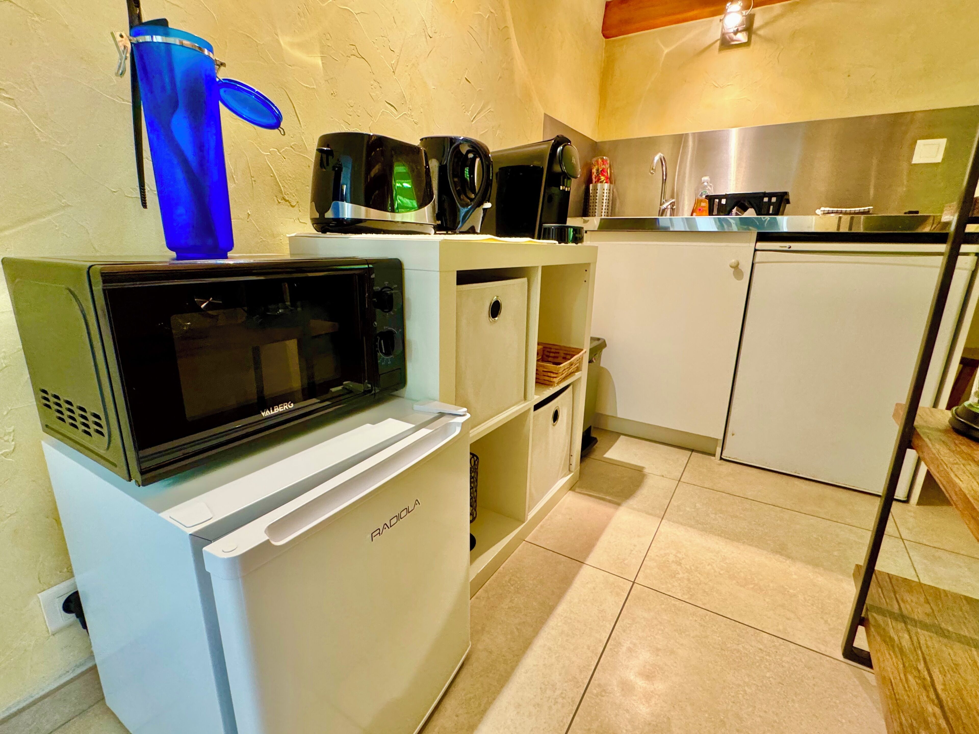 A compact kitchen with a built-in microwave, a small refrigerator, and a coffee maker.