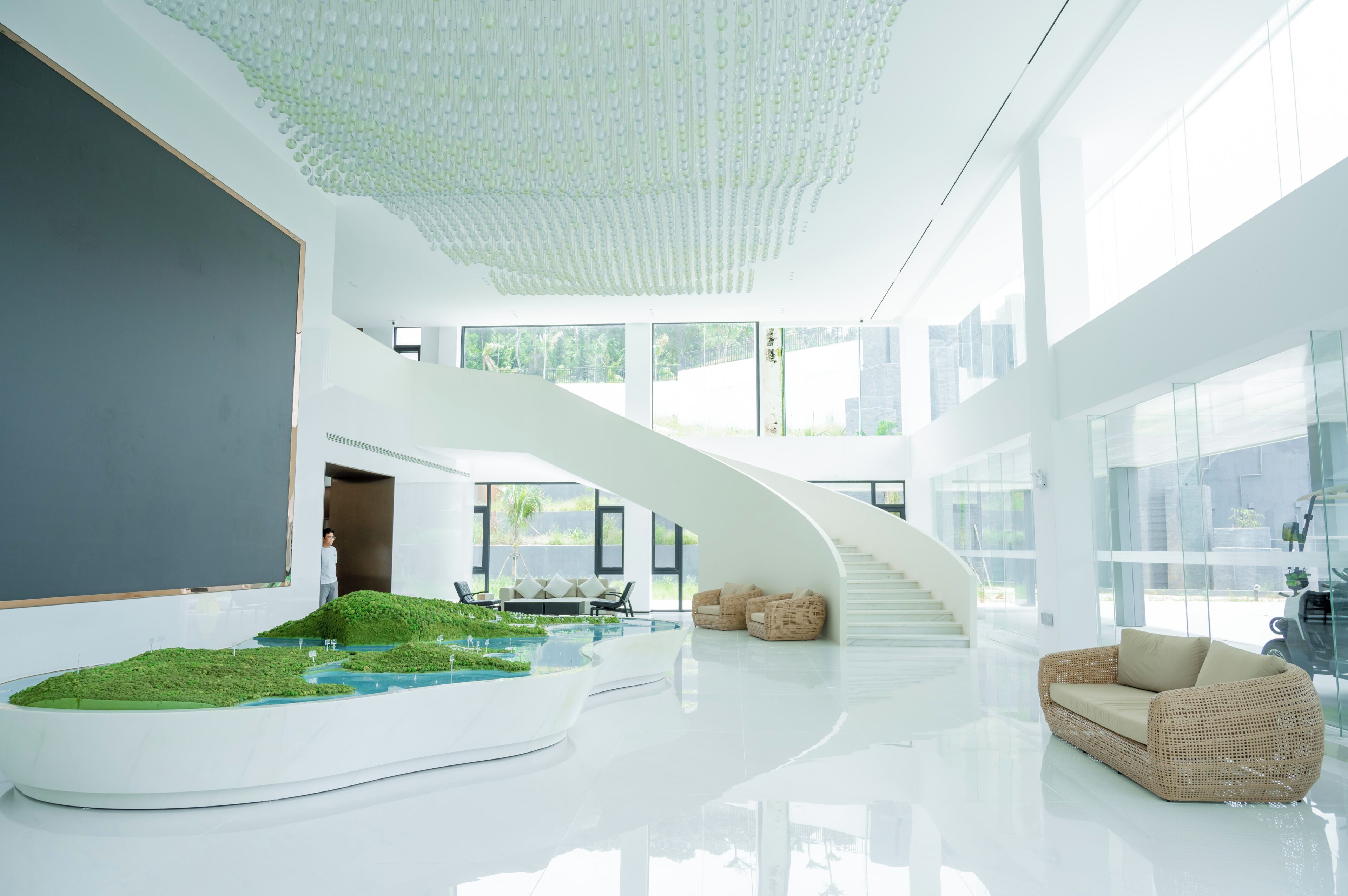 Um interior espaçoso com uma escadaria curva, área de estar e um elemento aquático.