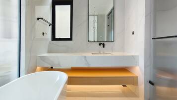 Un baño moderno con una bañera blanca, un espejo grande y una encimera de mármol.