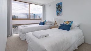 Ein Hotelzimmer mit zwei Betten, einem großen Fenster und Blick auf die Stadt.