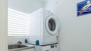 A compact laundry room with two stacked front-loading washers and a sink. - Forster Tower 64 in central Forster. (Forster)