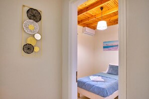 Een slaapkamer met een bed, een plafondventilator en een kunstwerk aan de muur.