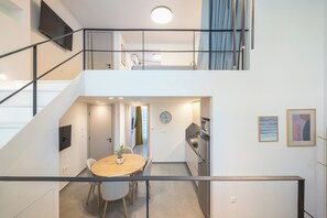 A modern apartment with a dining area, kitchen, and a staircase leading to a loft. - Athens Secluded Apartment A, Athens Secluded Apartments (Athens)