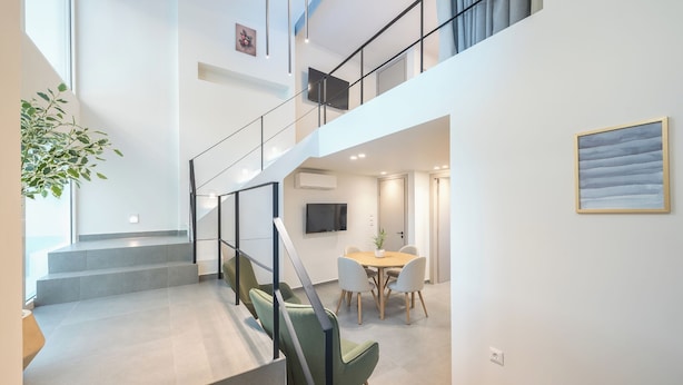 A modern interior with a staircase leading to a second floor, a dining area with a table and chairs, and a flat-screen TV mounted on the wall. - Athens Secluded Apartment A, Athens Secluded Apartments (Athens)