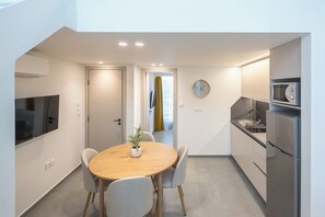 Une cuisine moderne avec un coin repas, comprenant une table et des chaises en bois, un four à micro-ondes et un réfrigérateur.