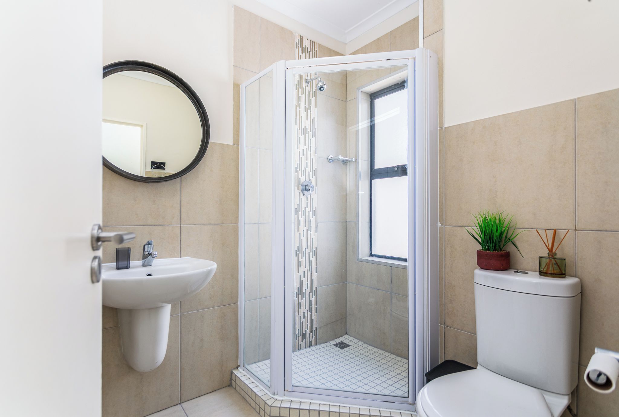 A modern bathroom with a glass-enclosed shower, a white sink, and a toilet.