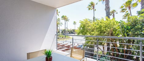 A balcony with a table, chairs, and a potted plant.
