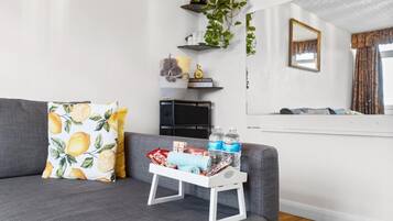 A living room with a grey sofa, a small white side table, and a mirror on the wall.