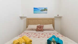 Una cama bien hecha con una colcha estampada con motivos florales, dos almohadas y toallas a un lado.