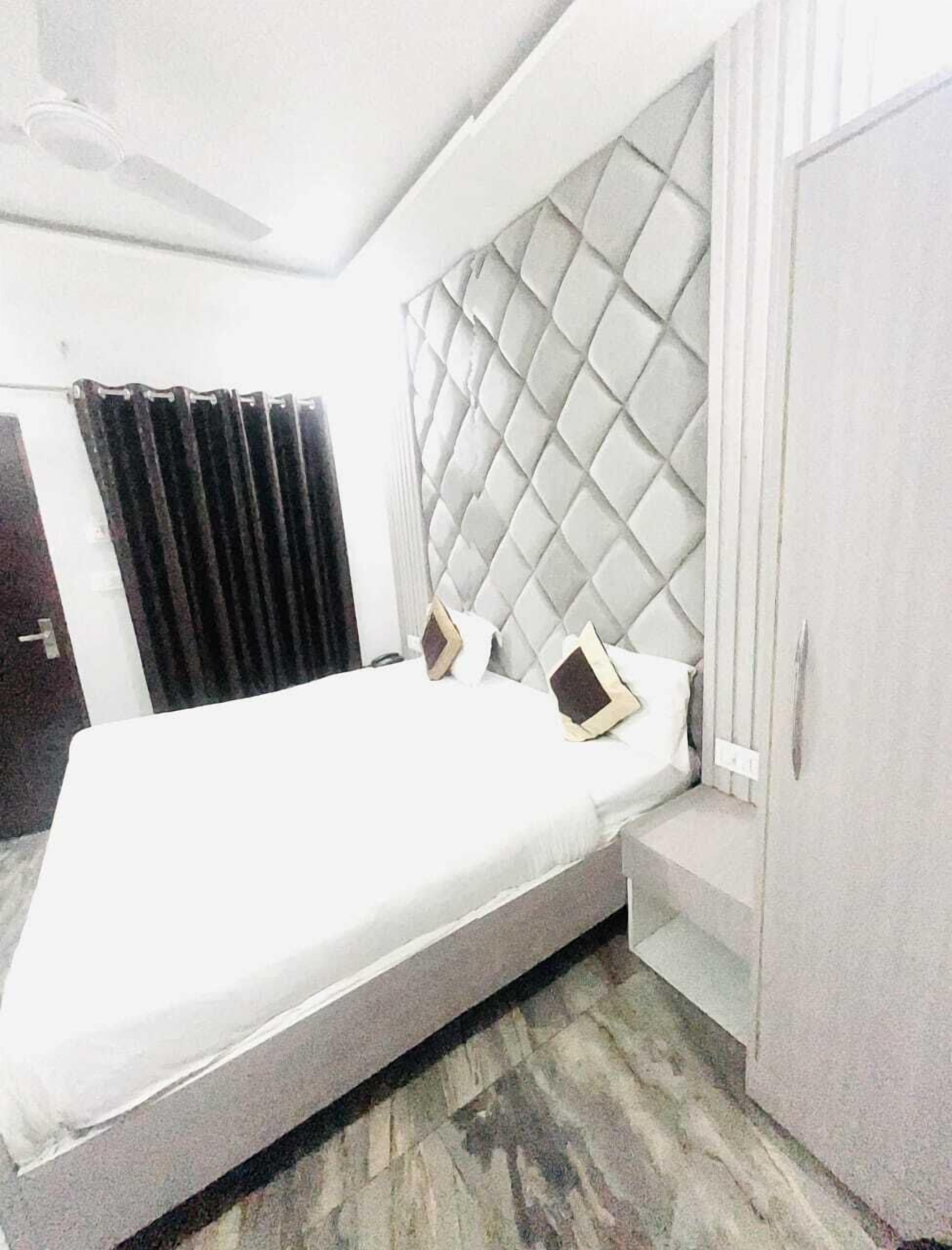 Une chambre d’hôtel moderne avec un grand lit, une armoire intégrée et un ventilateur de plafond.
