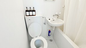 A bathroom with a toilet, a sink, and three bottles of liquid on the toilet tank. - XeroB HOUSE FLOLIA503 (osaka naniwa ward nanbanaka)
