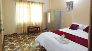 Una habitación de hotel con cama, ventilador de techo, ventana y espejo.