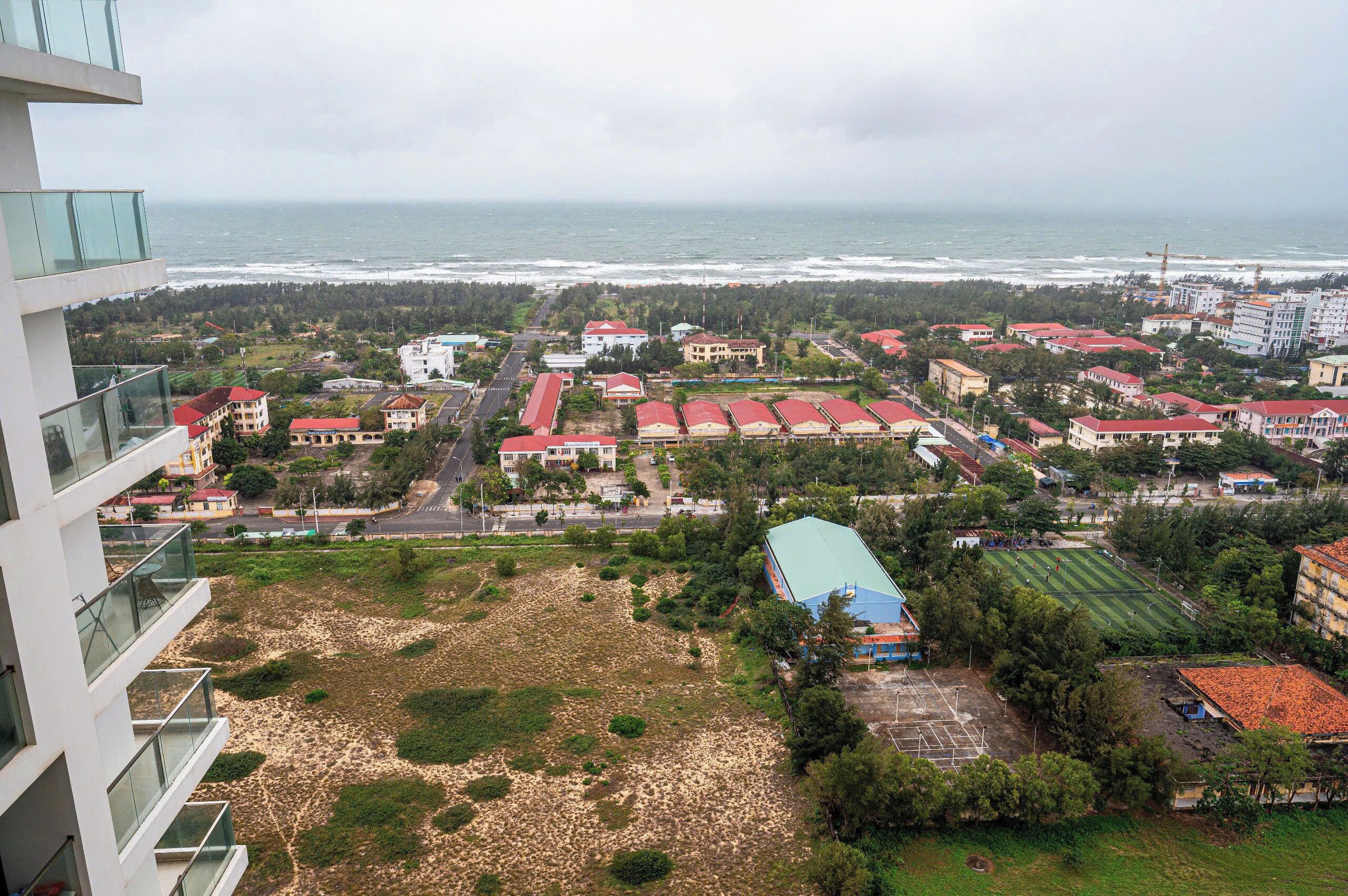 A coastal residential area with buildings, a beach, and a view of the ocean.