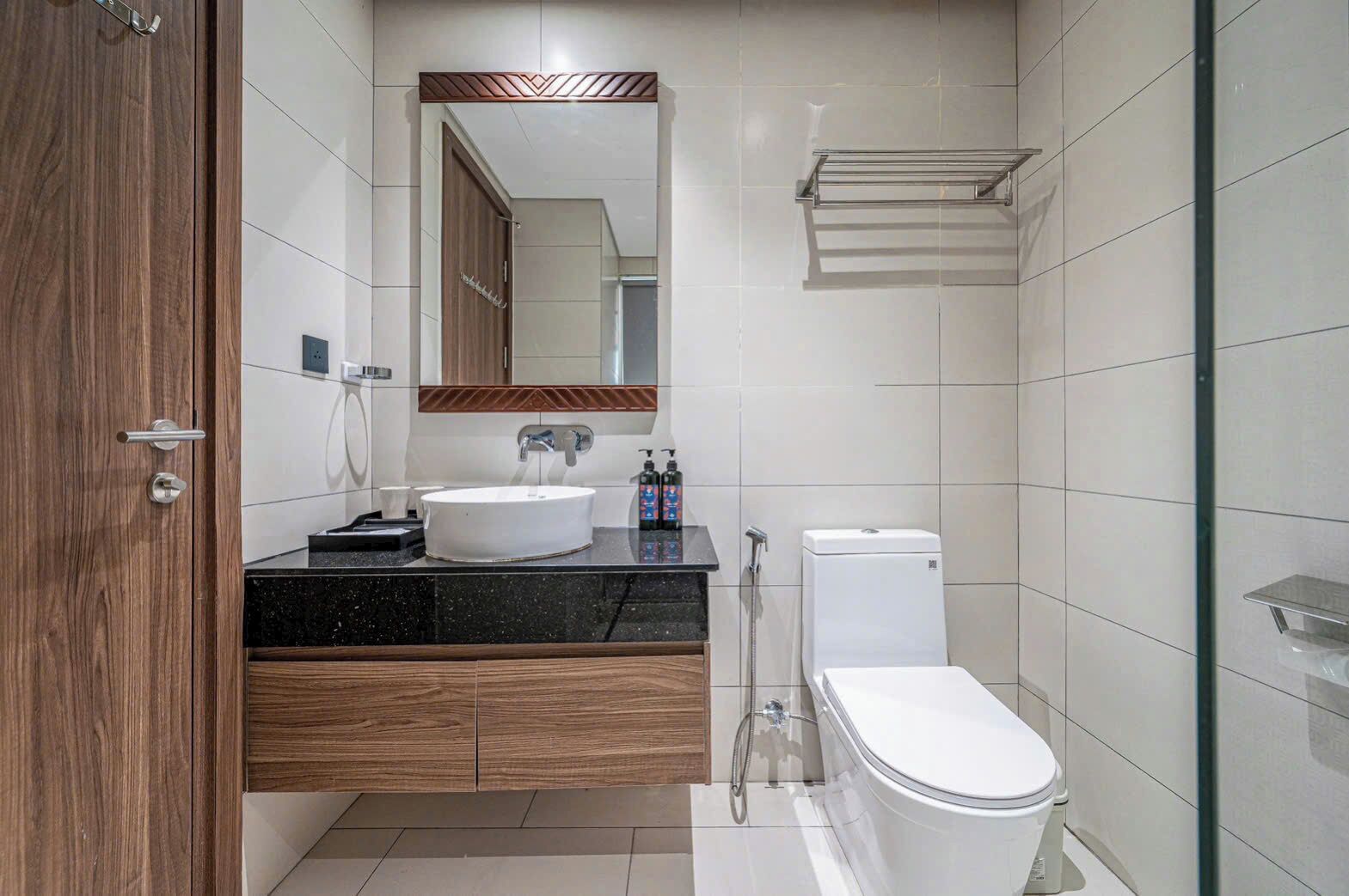 Een moderne badkamer met een houten wastafelmeubel, een witte wastafel, toilet en een douchecabine van glas.