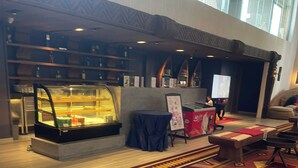 A hotel lobby with a display case, a patterned carpet, and a seating area.