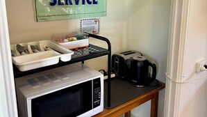 A kitchenette with a microwave, toaster, kettle, and a 'SERVICE' sign.