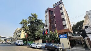 Un hotel con una facciata moderna, una targa e auto parcheggiate.