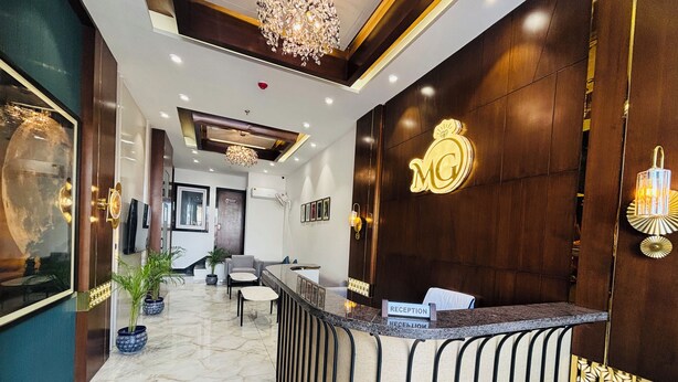 A hotel reception area with a marble floor, a reception desk, and a chandelier. - MG Plaza Hotel (Jodhpur)