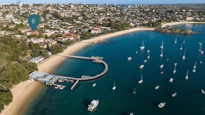 An aerial view of a coastal town with a marina, sandy beach, and residential buildings. - RAG25 - Balmoral Beach Lifesaver – Executive Listing (Mosman)