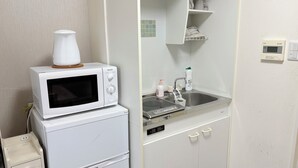 A compact kitchenette with a microwave, a small refrigerator, a sink, and a shelf with toiletries. - XeroB HOUSE FLOLIA601 (osaka naniwa ward nanbanaka)
