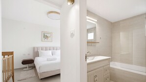 Un baño moderno con bañera, tocador y cama con cabecero.