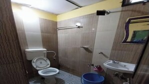 Baño pequeño con inodoro, lavamanos y un cubo azul.