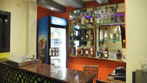 Una zona de bar con un refrigerador de Pepsi, estantes con botellas de licor y una barra.