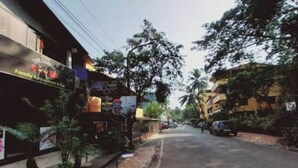 Vista de la calle con un restaurante llamado 'The Coast' a la izquierda, una acera con un pequeño árbol y un coche estacionado a la derecha.