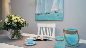 A table with a vase of flowers, a book, a cup, and two jars. - Exclusive Anker Mal Sylt vacation apartment with terrace and garden on the sandy beach (Sylt)