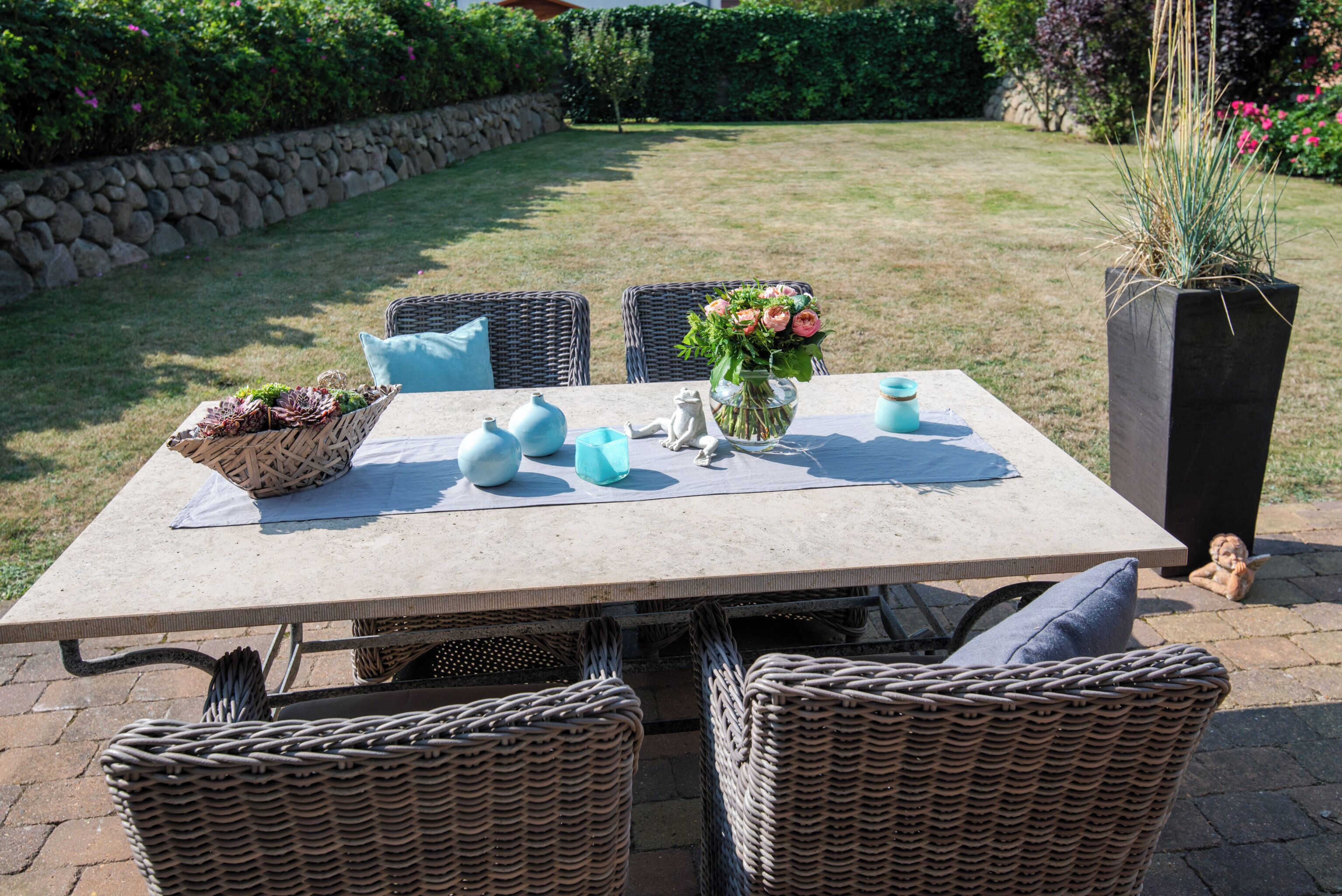 A patio with a table set for two, surrounded by wicker chairs.