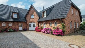 A two-story brick building with a grey tiled roof, a small window, and a door. - Exclusive Anker Mal Sylt vacation apartment with terrace and garden on the sandy beach (Sylt)
