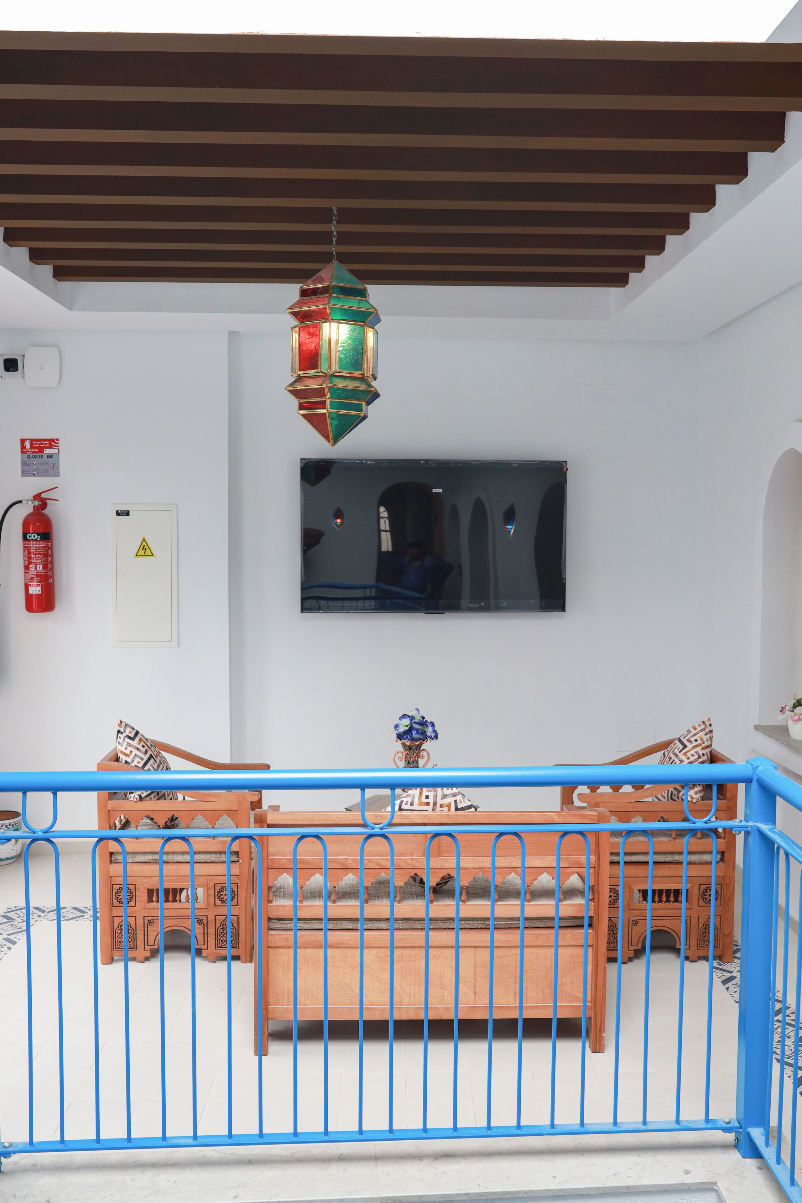 A room with a wooden bench, a television mounted on the wall, and a fire extinguisher on the wall.