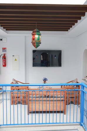 Una habitación con un banco de madera, un televisor montado en la pared y un extintor.