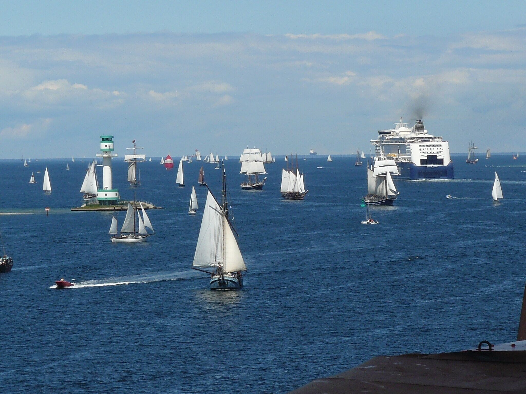 A harbor with multiple sailboats and a large cruise ship.