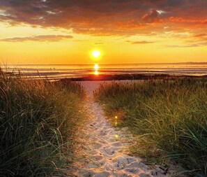 A beach path leading to the ocean with a sunset in the background. - Vacation apartment in Sahlenburg with sea view (Cuxhaven)