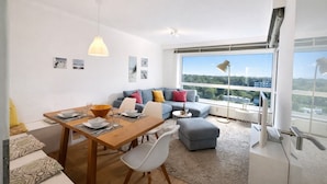 Una sala moderna con comedor, un juego de sofá y un ventanal con vistas a la ciudad.