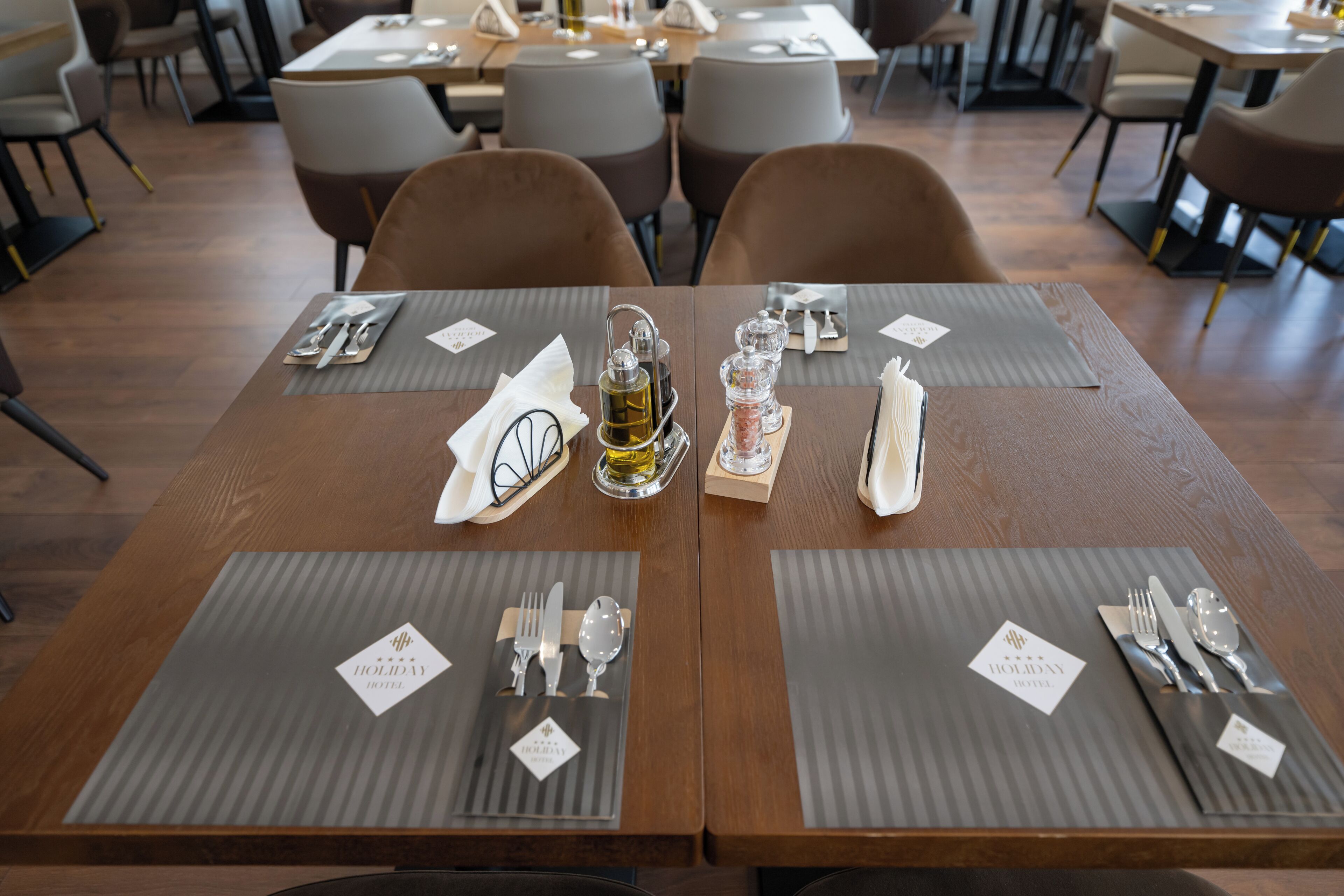 A dining table set with silverware, a glass of water, and a bottle of olive oil.