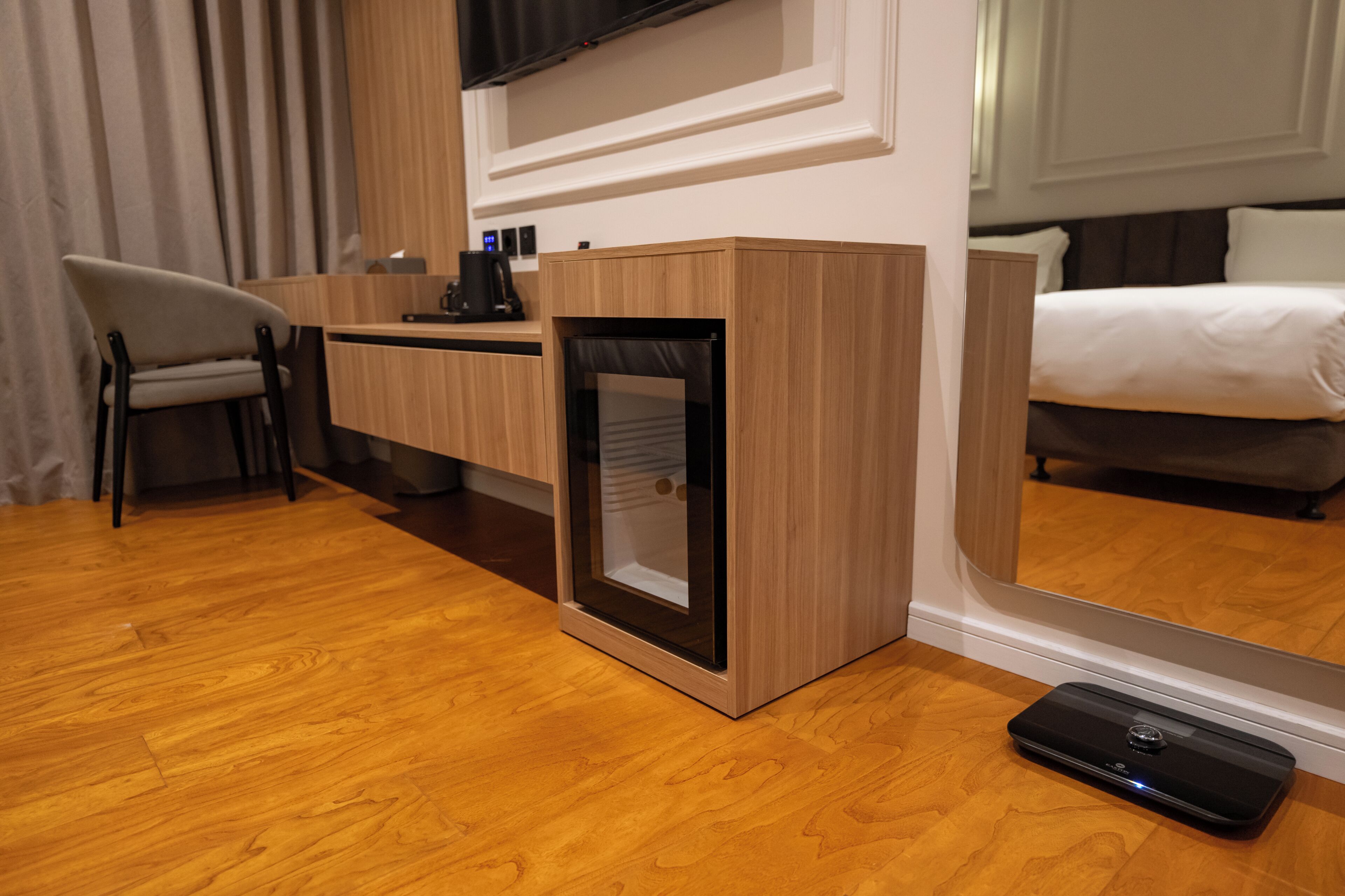 Habitación de hotel con escritorio de madera, una silla, una cama y un espejo grande.