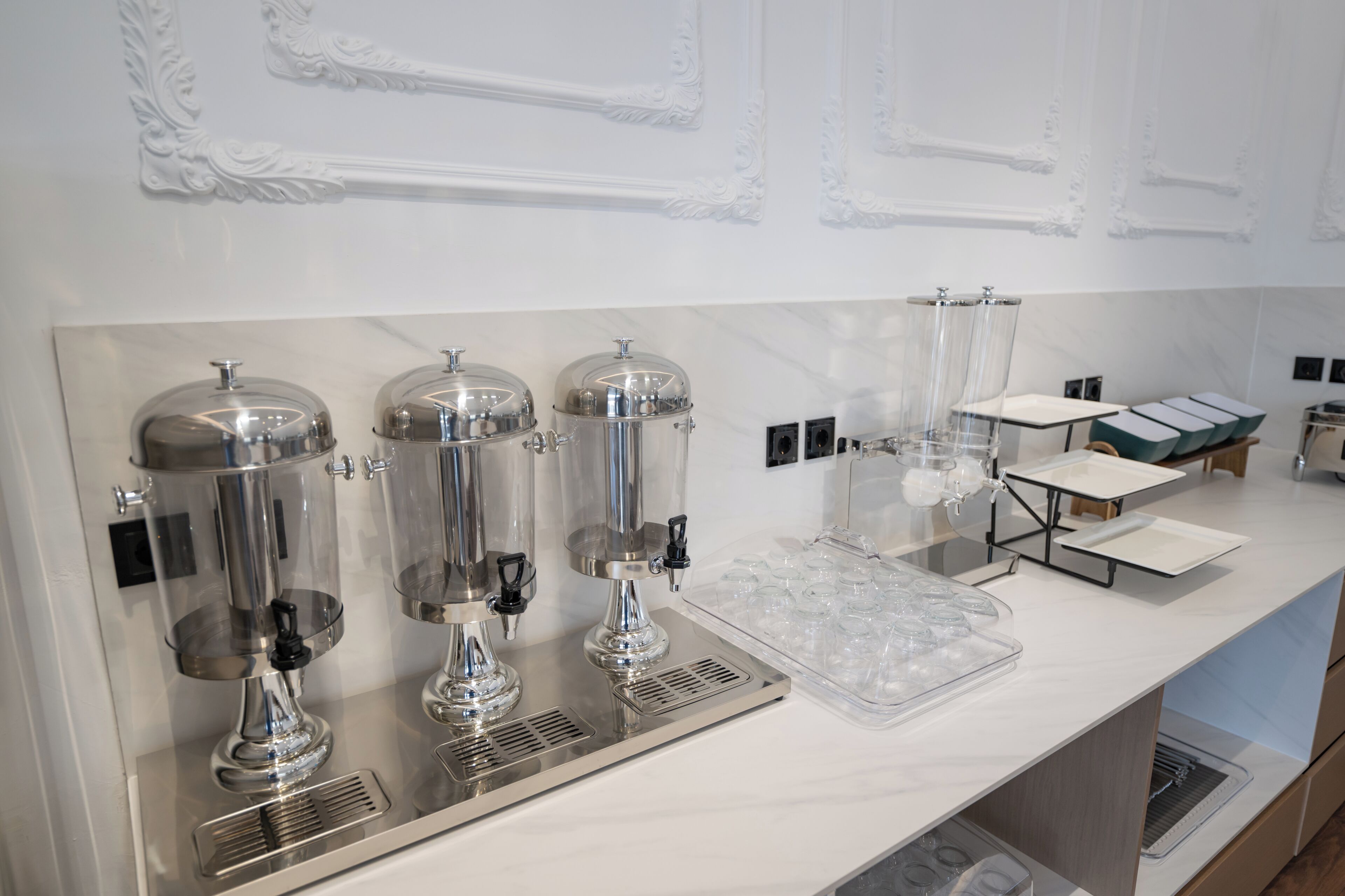 Un área de cocina con electrodomésticos de acero inoxidable, que incluye una cafetera y dispensador de agua.