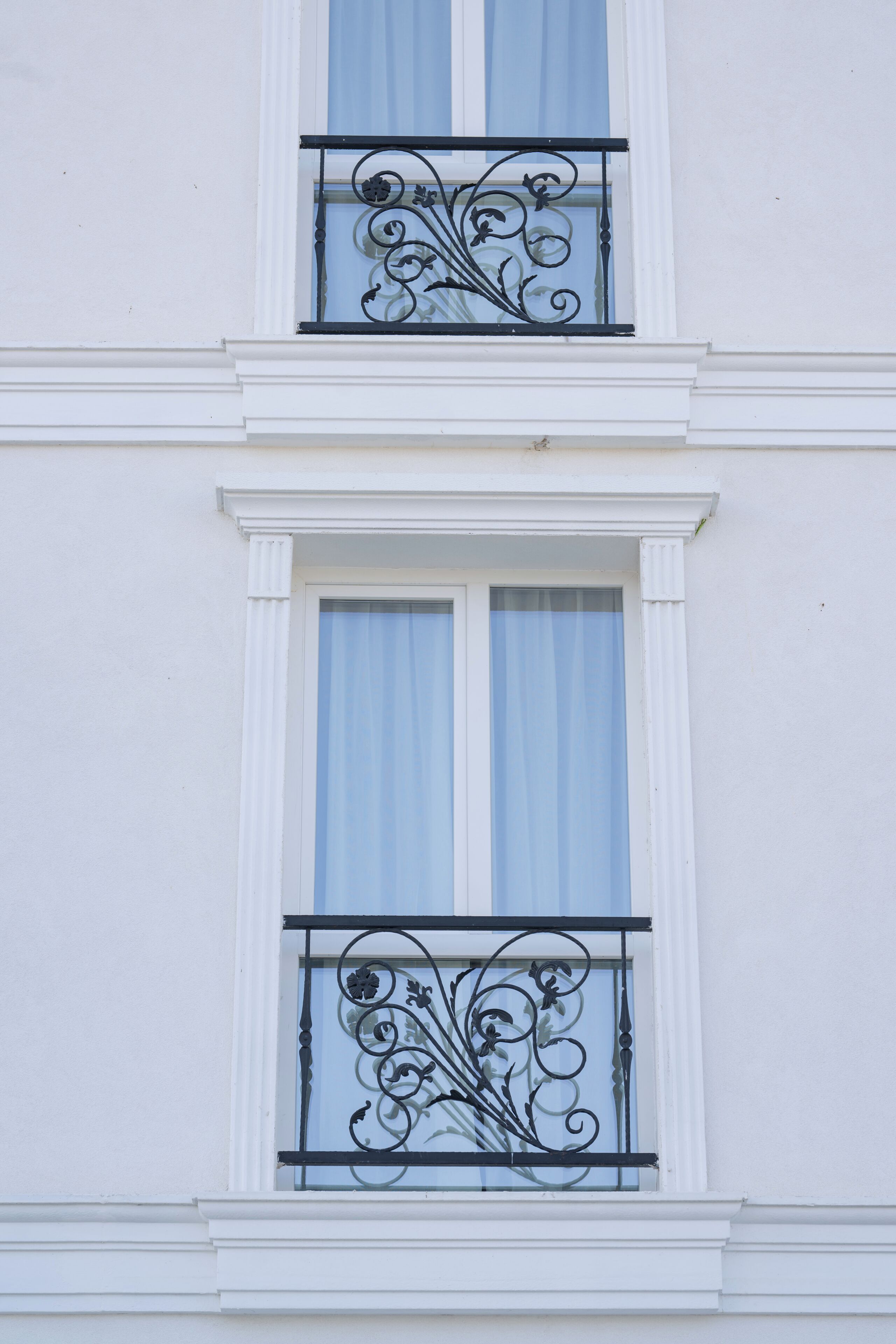 A building with two windows, each with a decorative wrought iron balcony.